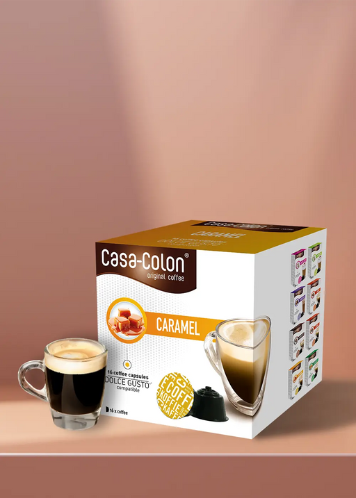 Une boîte de capsules Café Caramel pour votre machine Dolce Gusto est posée à côté d'un verre transparent de café au caramel fraîchement moulu, le tout sur un fond marron clair chaleureux. Régalez-vous de 16 délicieuses capsules qui vous apporteront un café au caramel de qualité professionnelle chez vous ! | Flaronis.lu