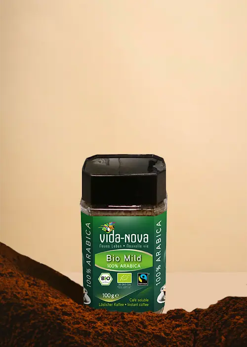 Un pot de café instantané 100 % Arabica doux Vida-Nova Bio trône fièrement sur un fond beige, mettant en valeur son étiquette verte ornée de logos de certification. Au premier plan, le café fraîchement moulu vous invite à savourer une infusion haut de gamme et respectueuse de l'environnement. | Flaronis.lu