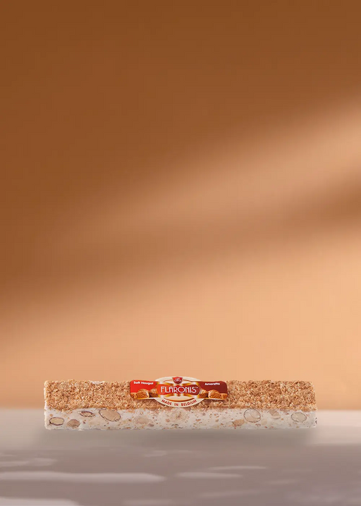 Un délicieux bloc de Turrón avec une base de nougat crémeux et des amandes croquantes, joliment emballé. Il est affiché sur un fond simple avec le nom de la marque bien en évidence sur l'étiquette. Parfaitement conçu pour compléter vos moments café ! | Flaronis.lu