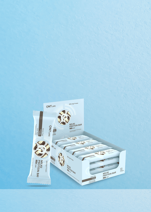 Imaginez un emballage bien droit de « QNT Protein Milki 28% Low Sugar Coconut Flakes 60G » présenté de manière attrayante à côté d'une boîte ouverte remplie de délicieuses barres. Le fond bleu clair met magnifiquement en valeur ce plaisir sain, avec des notes subtiles de saveur de flocons de noix de coco, parfait pour les amateurs de café à la recherche d'un compagnon délicieux pour leur boisson préférée. | Flaronis.lu