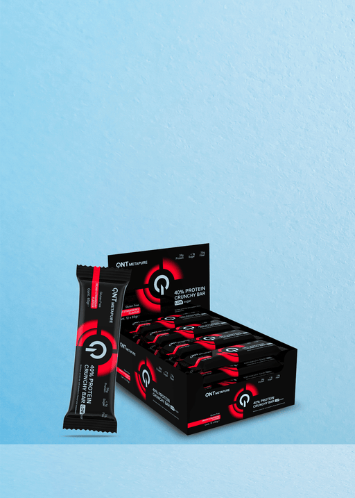 Découvrez la barre A QNT 40% Protein Crunchy Low Sugar Creamy Strawberry, parfaitement posée à côté de sa boîte sur un fond bleu texturé. Présentée dans un élégant emballage noir et rouge, cette barre est une collation à faible teneur en sucre idéale pour les amateurs de café qui refusent de faire des compromis sur le goût ou les protéines. Dégustez-la avec votre boisson préférée pour un accord satisfaisant et énergisant. | Flaronis.lu