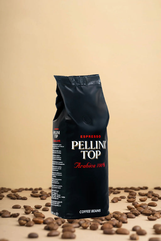 Découvrez l'élégance du café avec un élégant présentoir présentant un sac noir de 500 g de grains Pellini Top 100 % Arabica. Imaginez ces grains de café haut de gamme, disposés avec art sur une surface beige chaleureuse, vous invitant à savourer leur arôme riche et leur saveur exquise. Parfait pour les vrais amateurs de café !. | Flaronis.lu